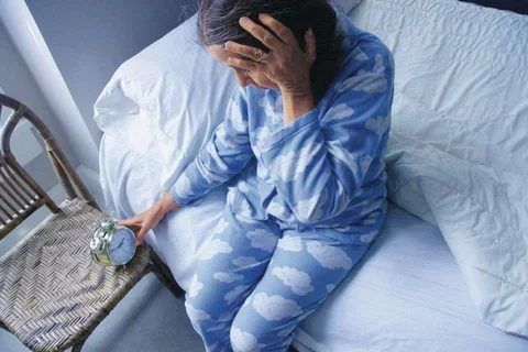 Woman checks alarm clock in bed