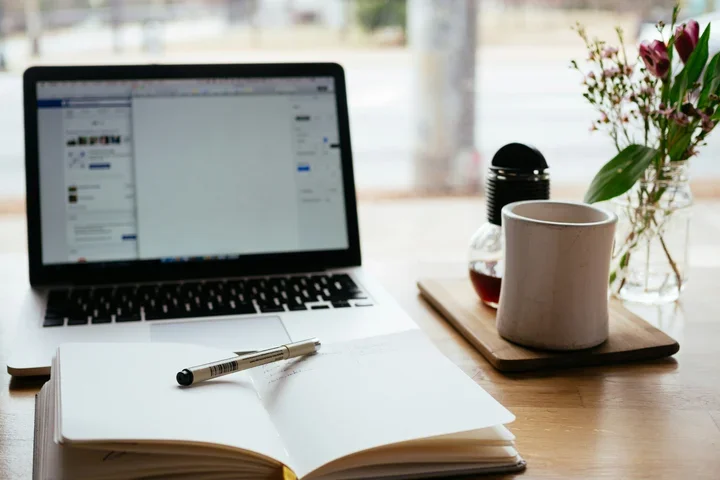 Computer with a mug and journal beside it