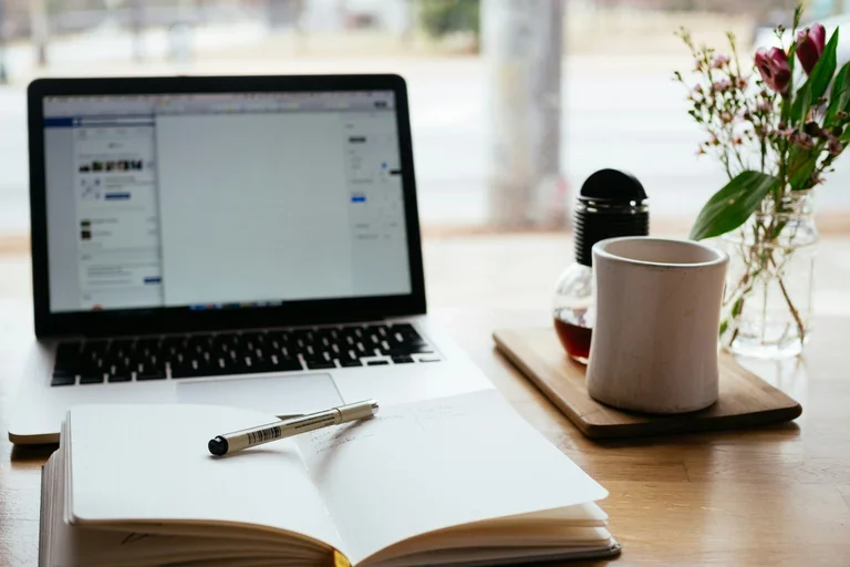 Computer with a mug and journal beside it