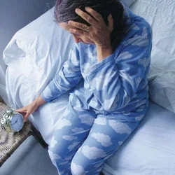 Woman checks alarm clock in bed