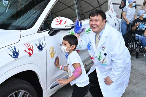 Dr. Steven Jonas and a patient at UCLA Mattel Children's Hospital put their handprints on a Hyundai during a celebration of Dr. Jonas receiving a $400,000 grant